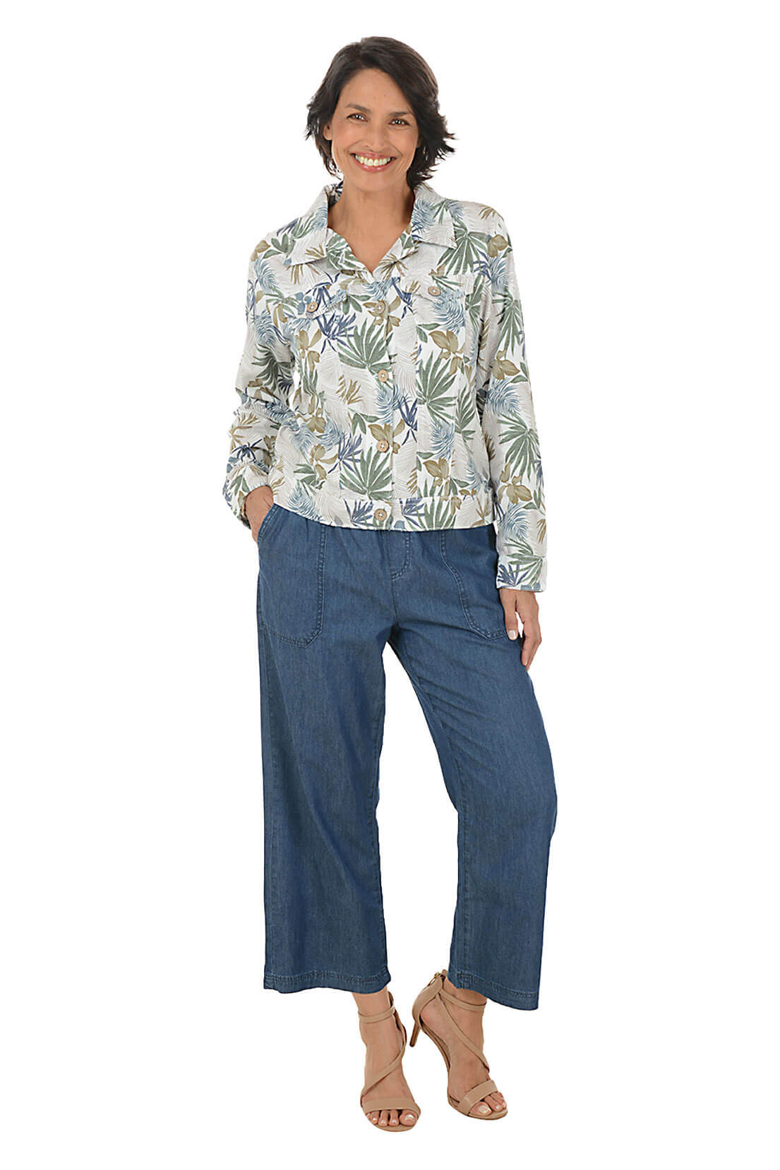 Woman wearing a patterned blouse and blue pants on a white background
