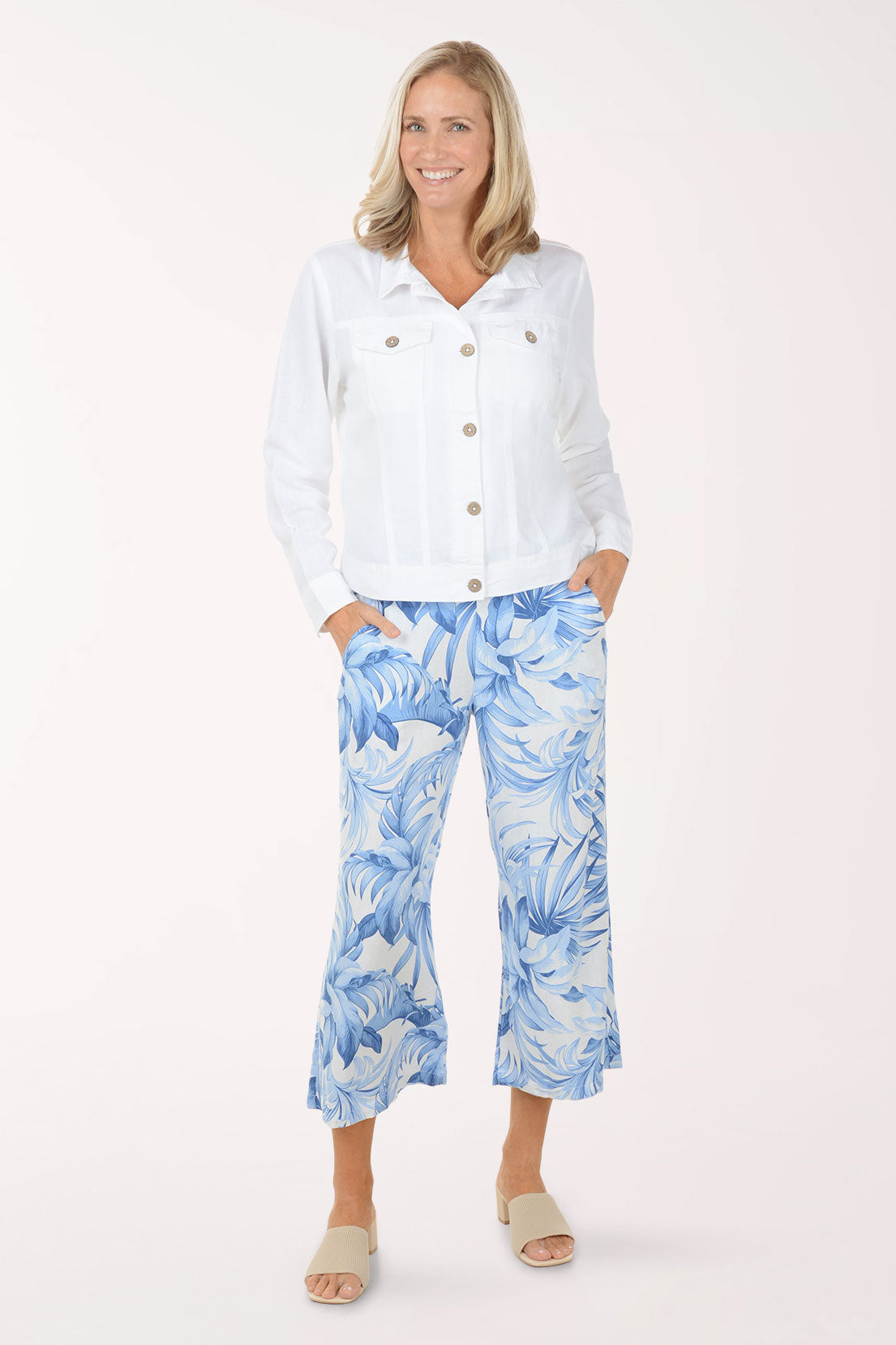 Woman wearing a white shirt and blue floral pants on a white background
