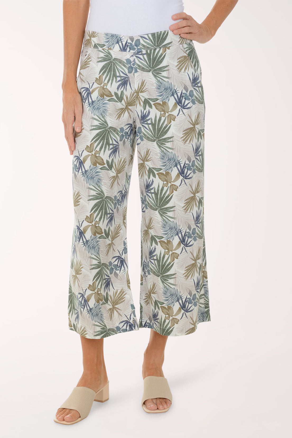Person wearing tropical leaf patterned pants on a white background