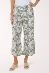 Person wearing tropical leaf patterned pants on a white background
