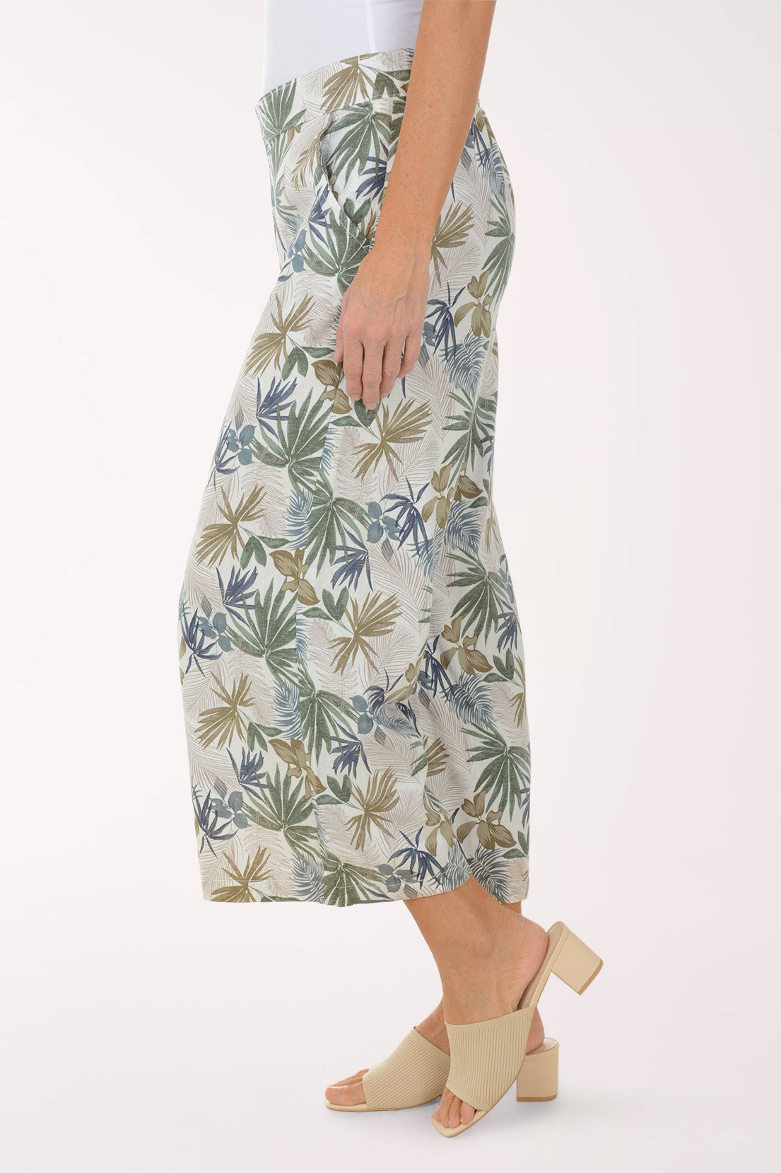 Person wearing tropical leaf patterned pants on a white background
