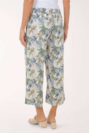 Person wearing tropical leaf patterned pants on a white background