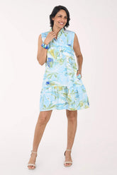 Woman wearing a sleeveless, light blue dress with green floral pattern on a white background