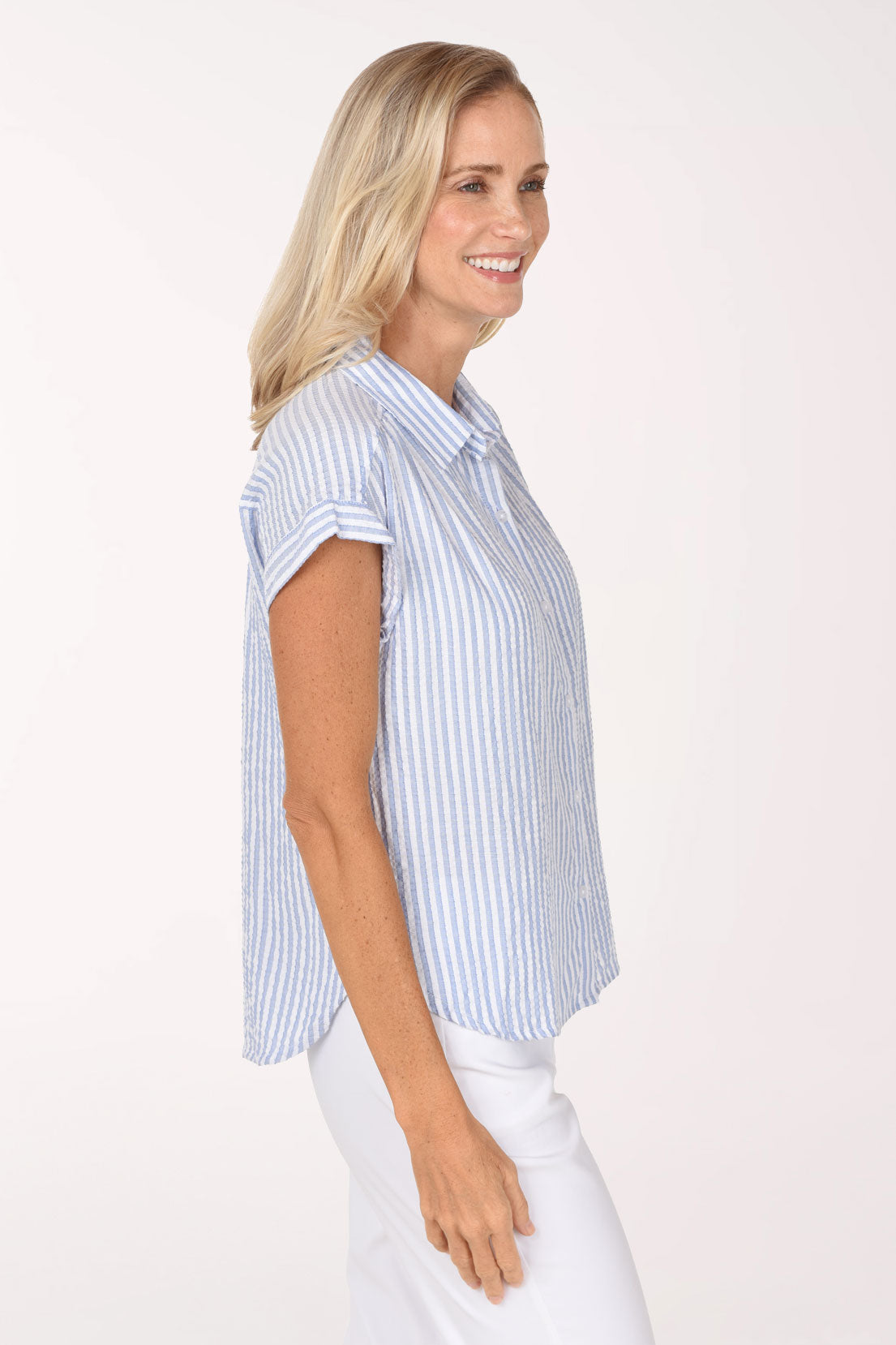Woman wearing a cap sleeve button up shirt with a seersucker blue and white stripe pattern