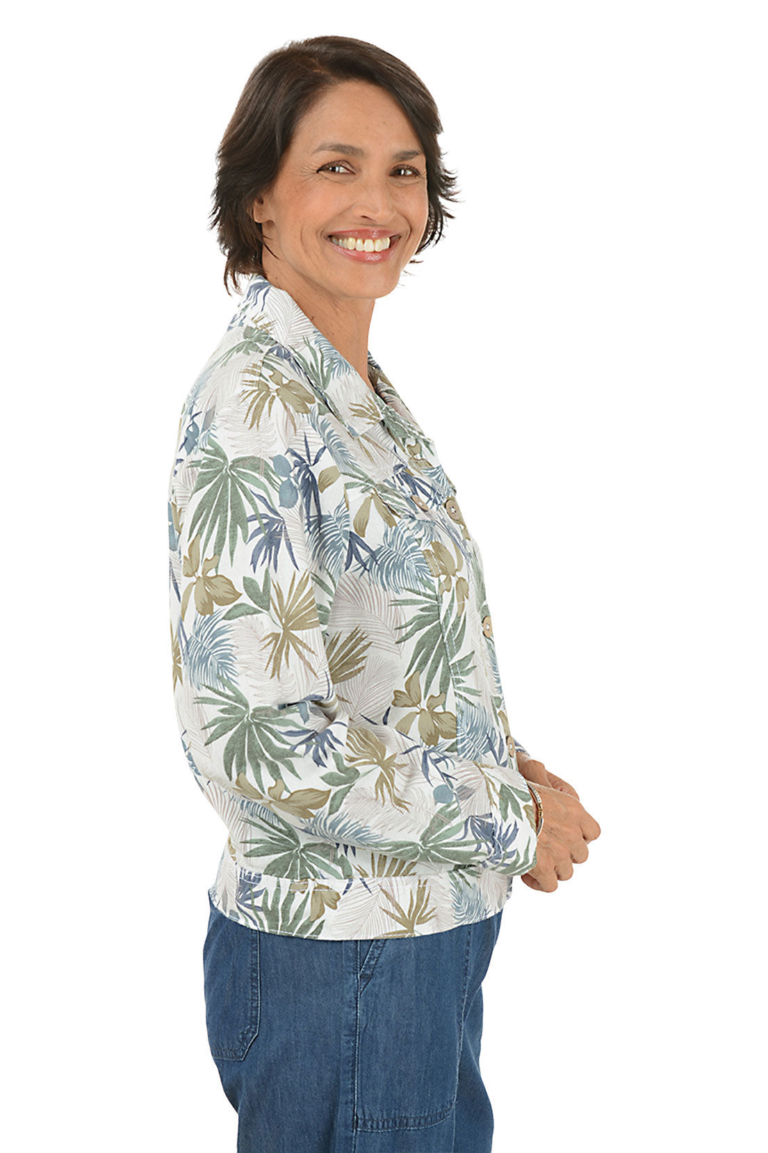 Woman wearing a floral patterned jacket and blue pants on a white background. Side shot.