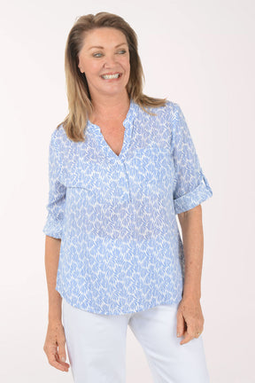 Woman wearing a light blue patterned shirt on a white background