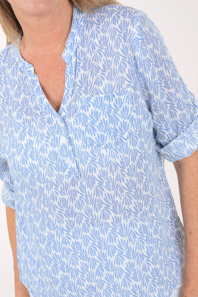 Woman wearing a light blue patterned shirt on a white background