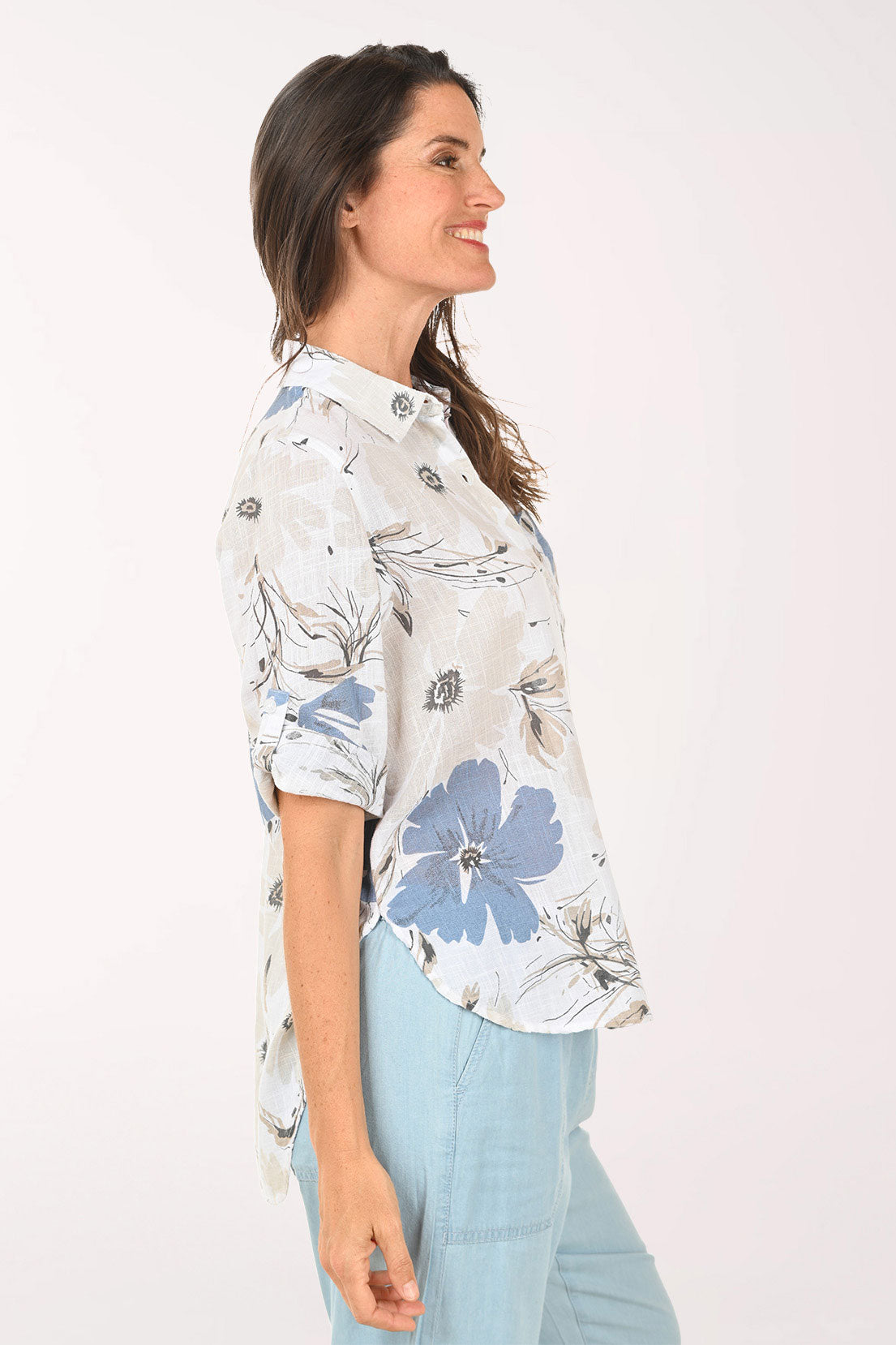Woman wearing a tan and blue floral button down top.