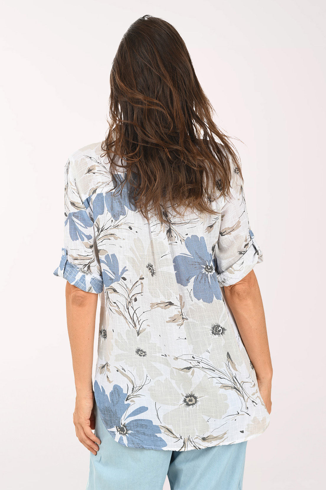 Woman wearing a tan and blue floral button down top.