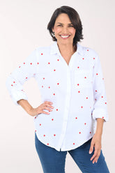 Woman wearing a white button down shirt with embroidered hearts