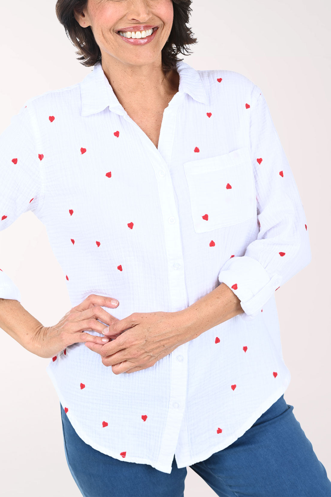 Woman wearing a white button down shirt with embroidered hearts