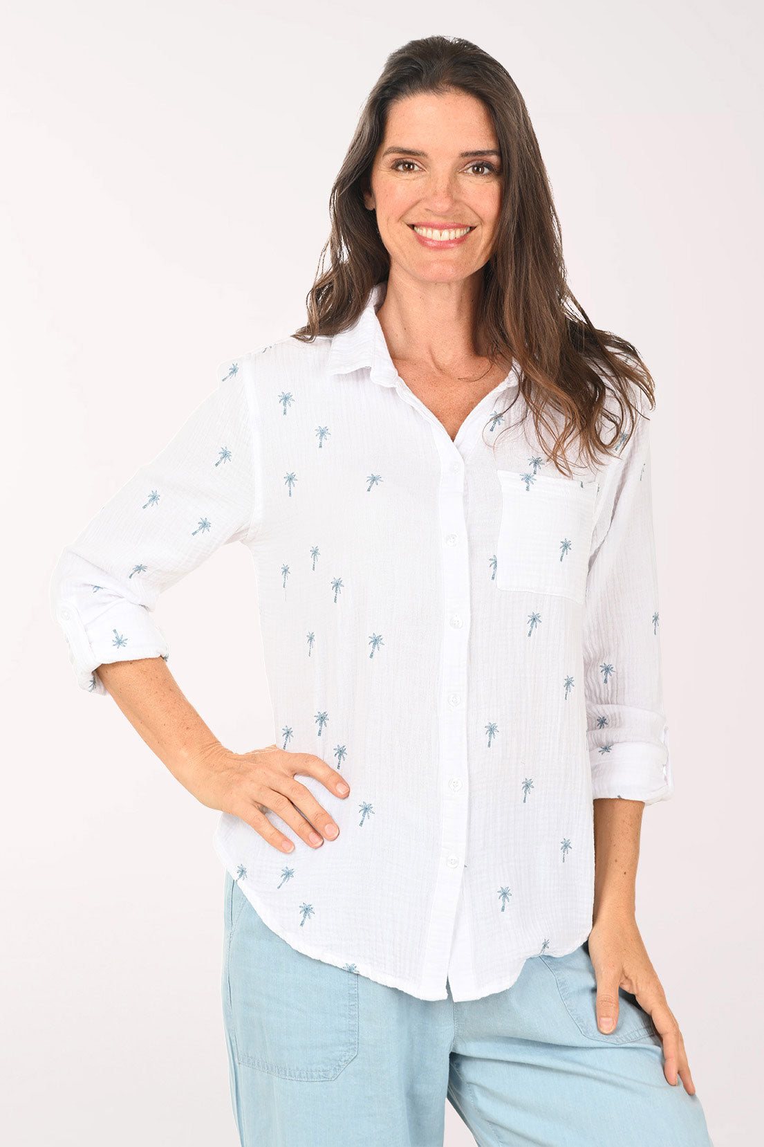 Woman wearing a 3/4 sleeve white top with embroidered palm trees