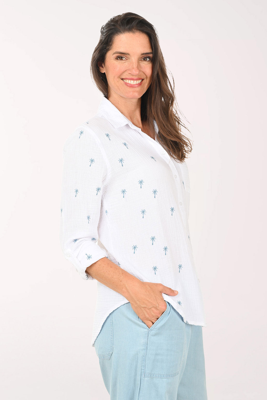 Woman wearing a 3/4 sleeve white top with embroidered palm trees