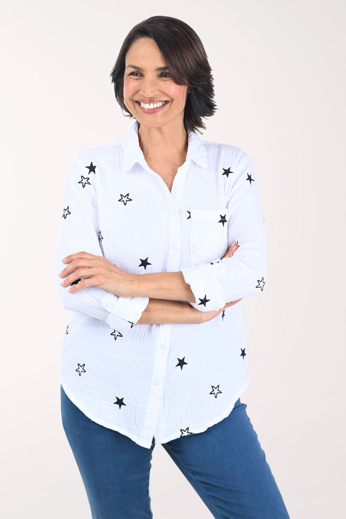 Woman wearing a white shirt with black star patterns on a plain background