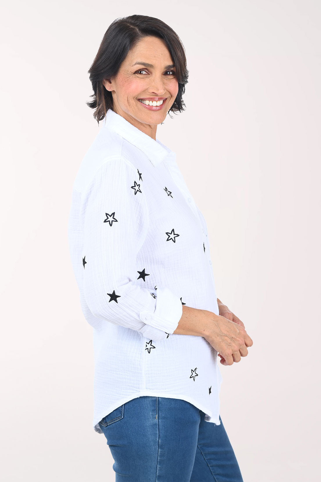 Woman wearing a white shirt with black star patterns on a plain background