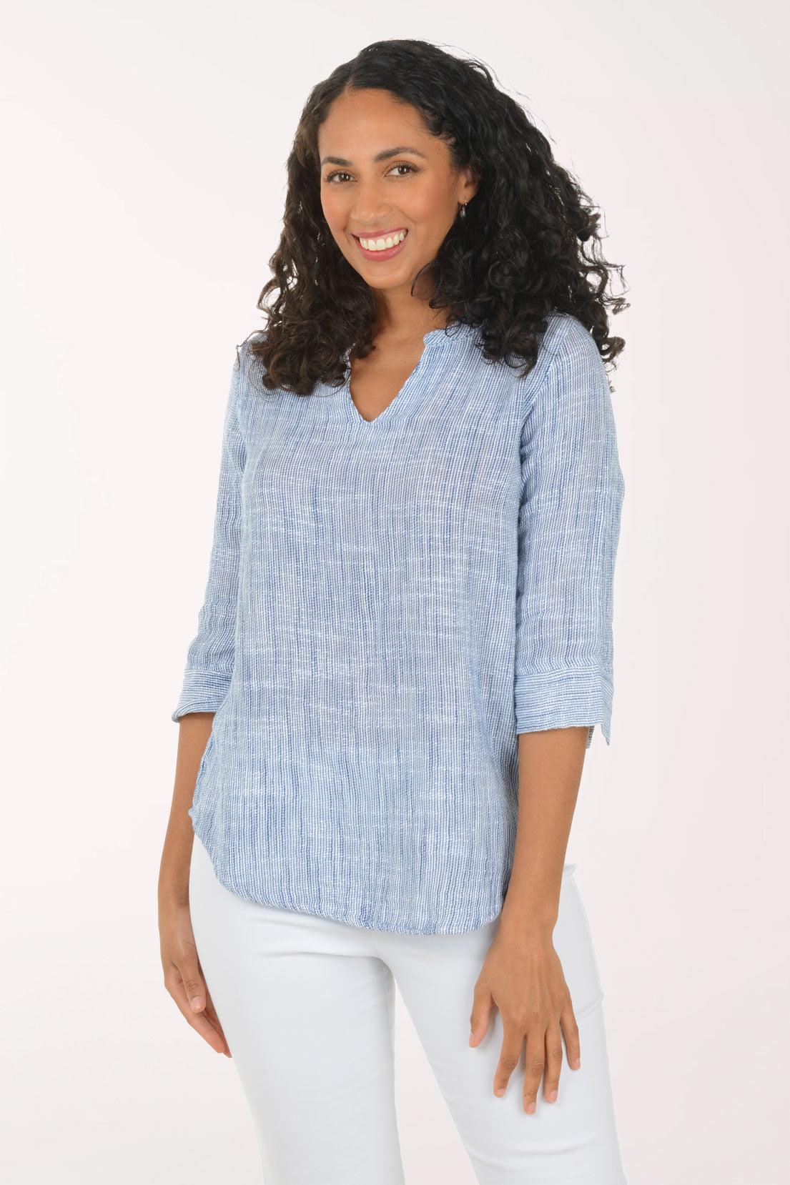 Woman wearing a blue checkered blouse and white pants on a white background