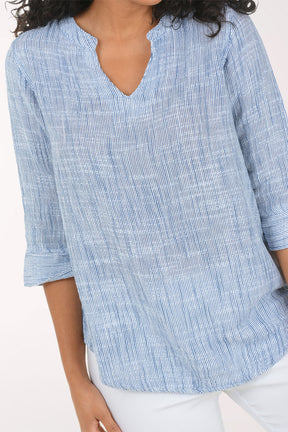 Woman wearing a blue checkered blouse and white pants on a white background