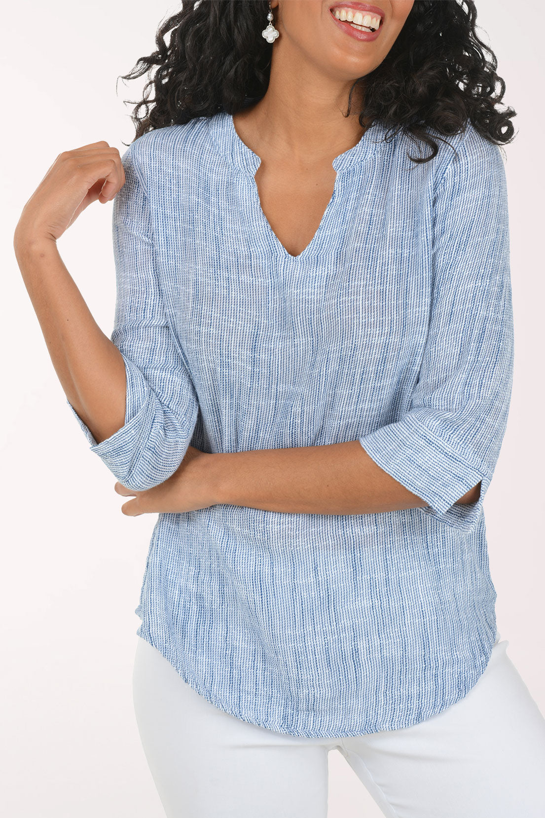 Woman wearing a blue checkered blouse and white pants on a white background