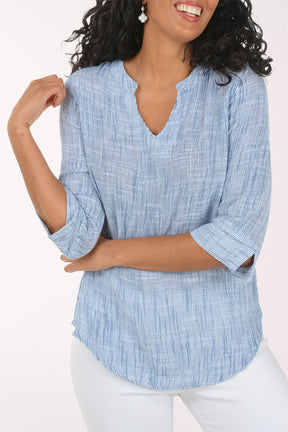 Woman wearing a blue checkered blouse and white pants on a white background