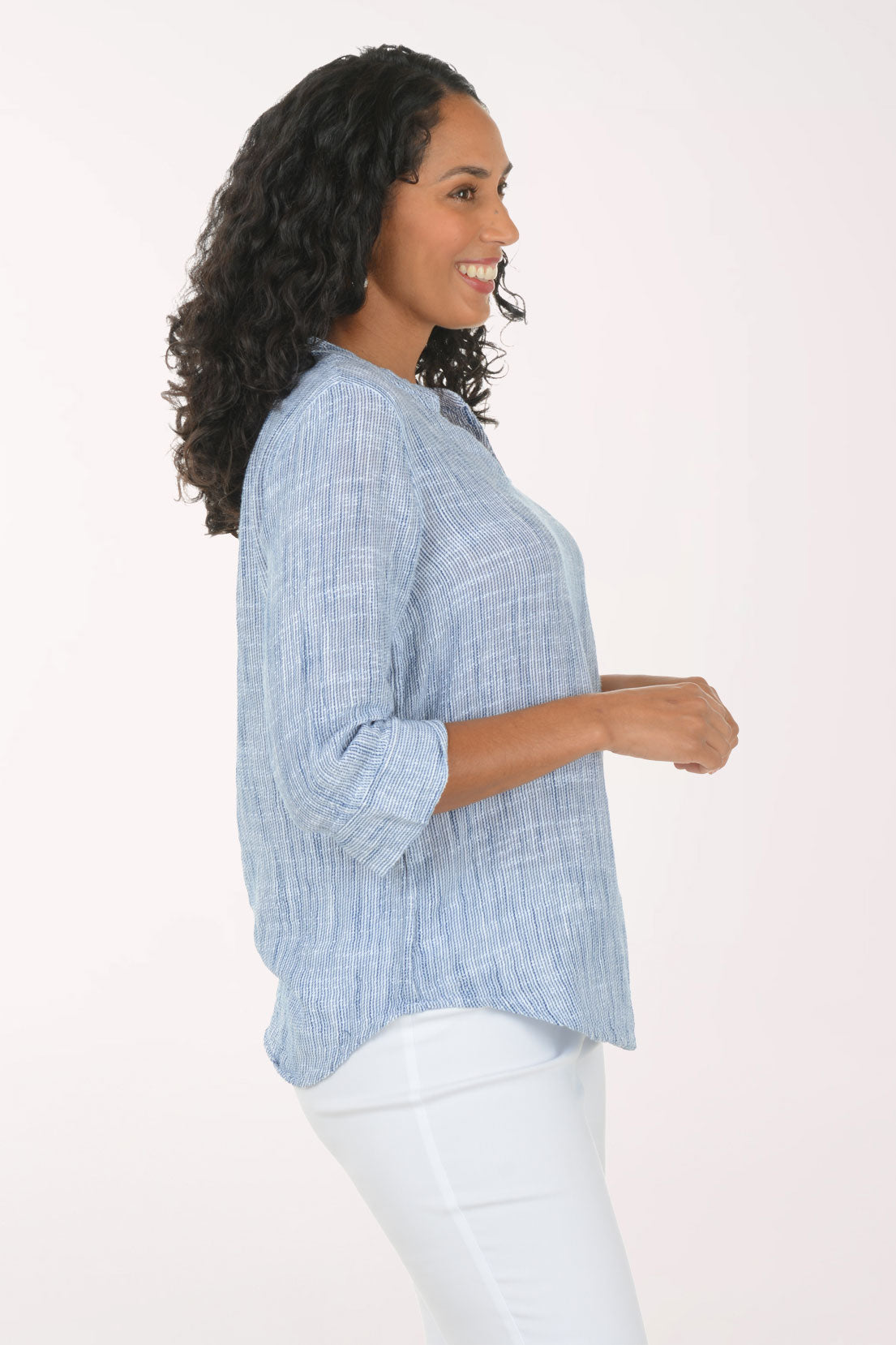 Woman wearing a blue checkered blouse and white pants on a white background
