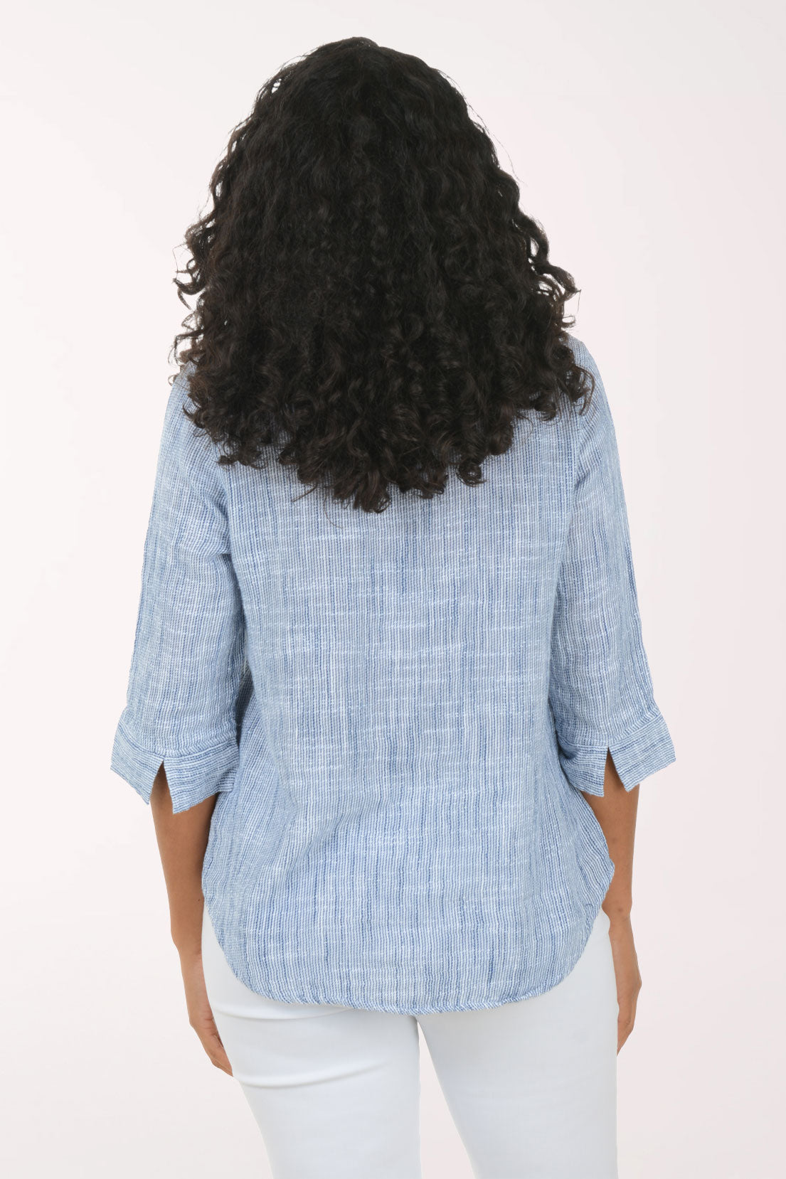 Woman wearing a blue checkered blouse and white pants on a white background