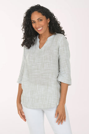 Woman wearing a light gray checkered blouse with white pants on a white background