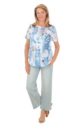 Woman wearing a blue floral blouse and light blue jeans on a white background