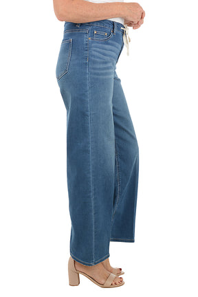 Blue jeans with a drawstring waist on a white background. Side shot.