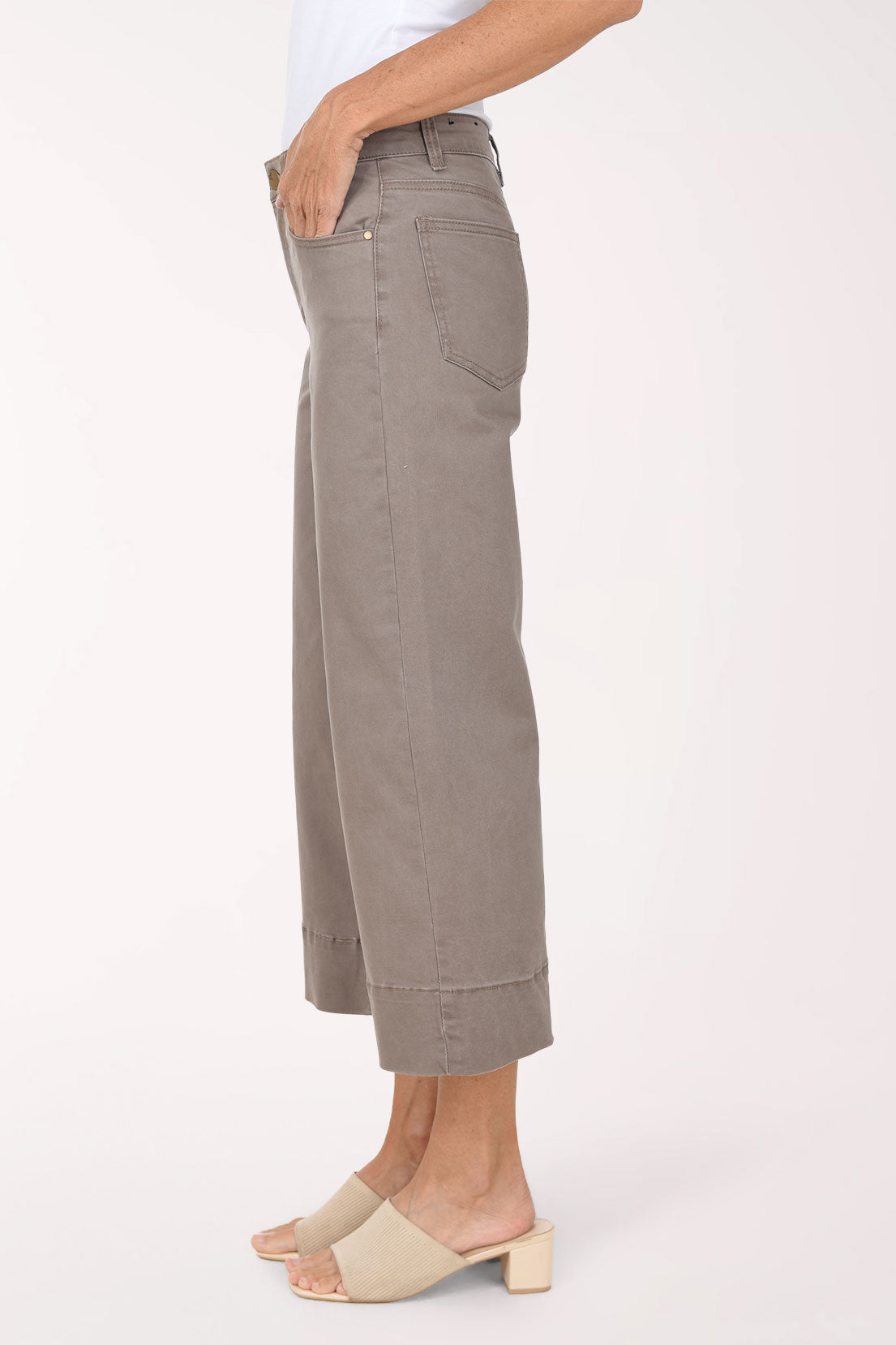 A model wearing a pair of taupe cropped wide-leg jeans with rolled hems, paired with beige slide sandals, against a plain light background.