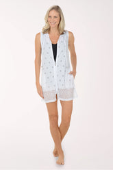 Woman wearing a white sleeveless top with lace trim on a white background