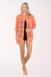 Woman wearing a coral crochet cover-up on a white background