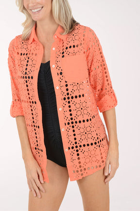 Woman wearing a coral crochet cover-up on a white background