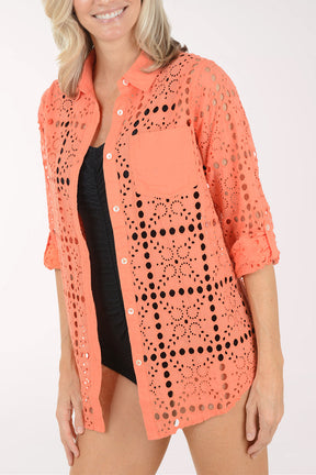 Woman wearing a coral crochet cover-up on a white background