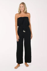 Woman wearing a black strapless jumpsuit on a white background