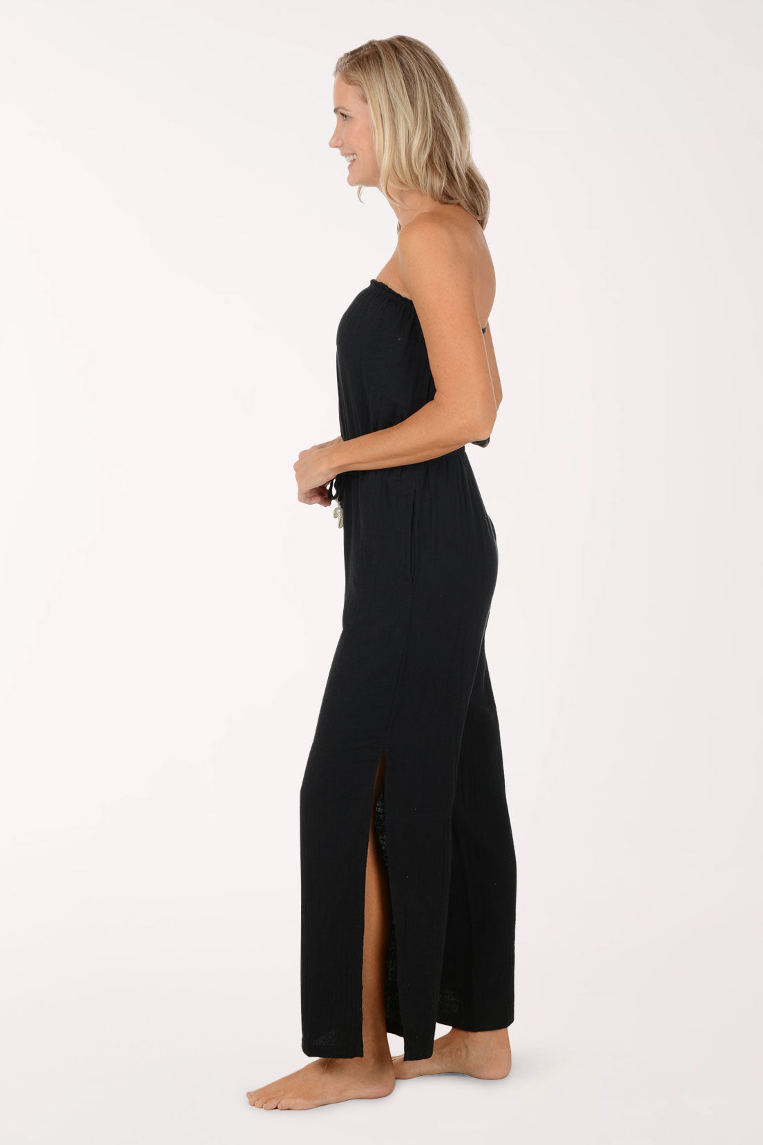 Woman wearing a black strapless jumpsuit on a white background