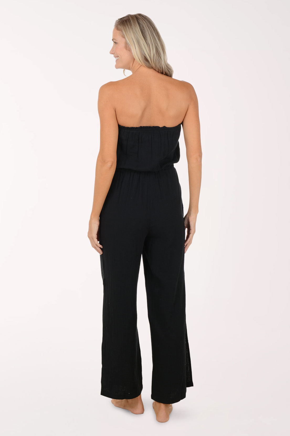Woman wearing a black strapless jumpsuit on a white background