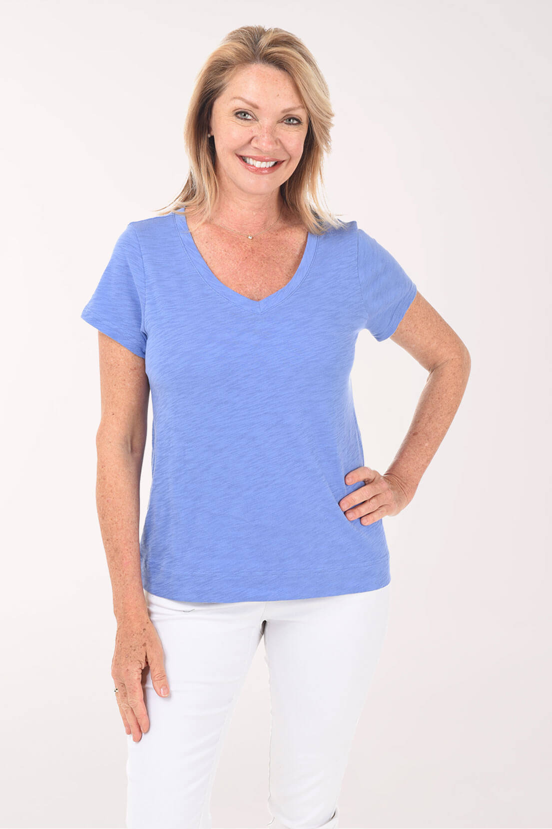 Woman wearing a blue t-shirt and white pants on a white background