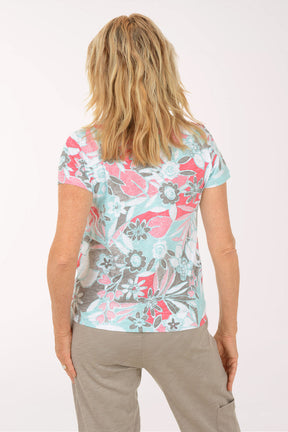 A woman wearing a short sleeve multicolored floral top.