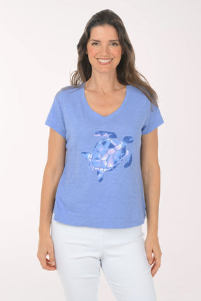A woman wearing a short sleeve blue top with a turtle print.