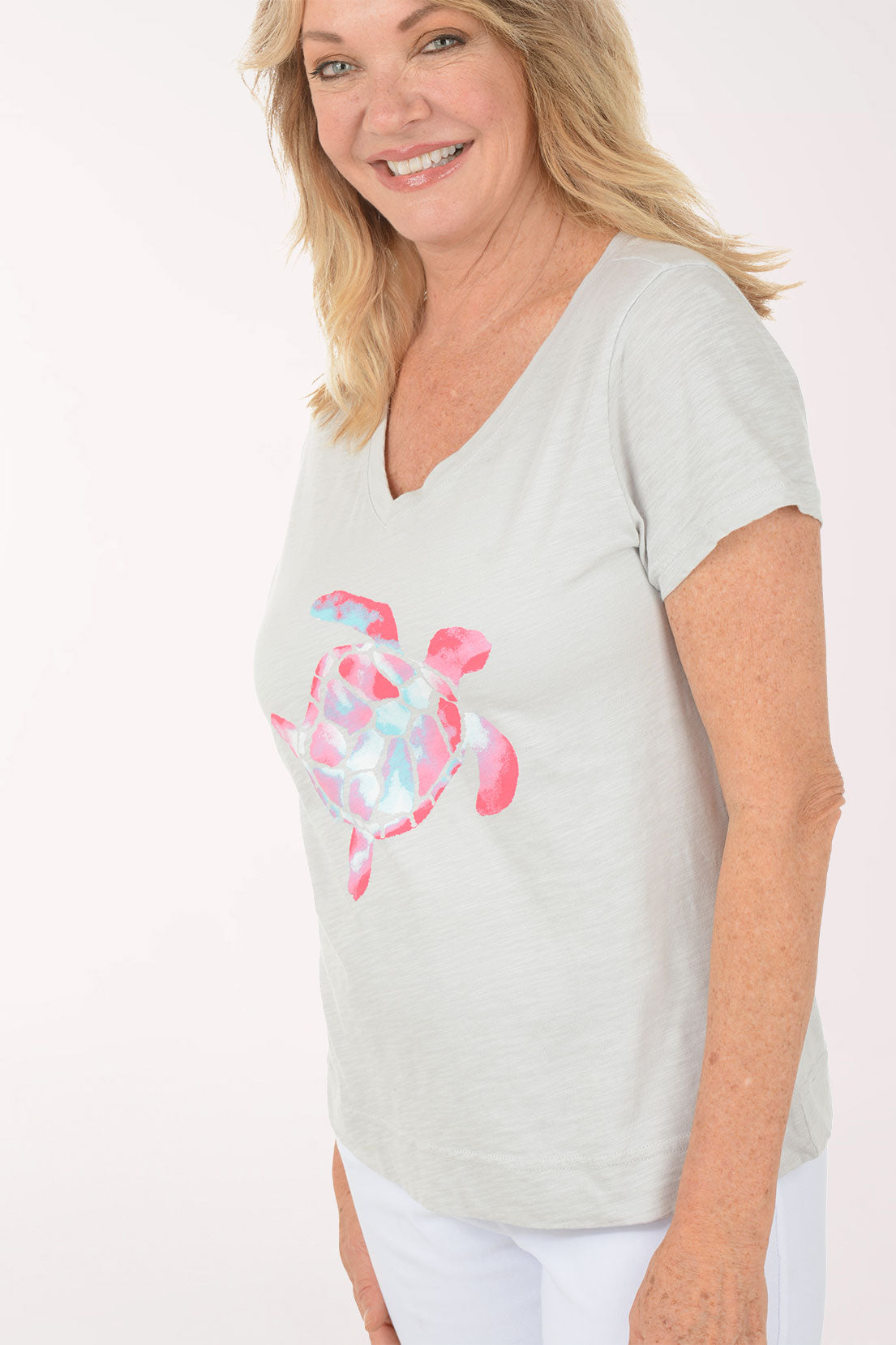 A woman wearing a short sleeve grey top with a turtle print.