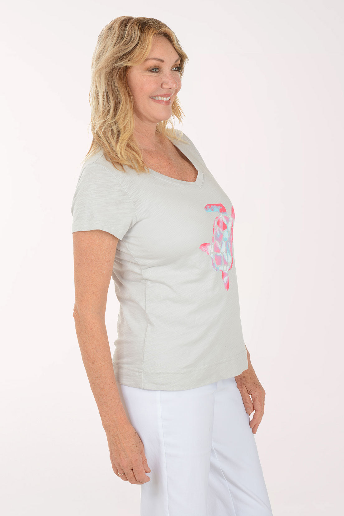A woman wearing a short sleeve grey top with a turtle print.