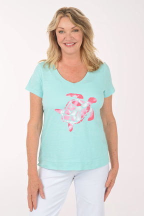 A woman wearing a short sleeve blue top with a turtle print.