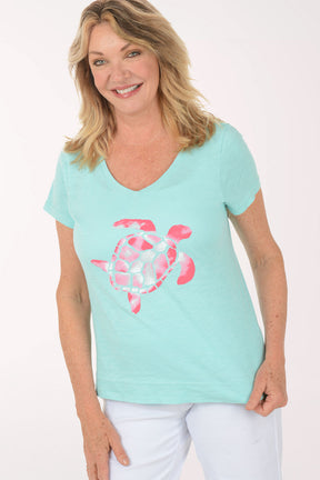 A woman wearing a short sleeve blue top with a turtle print.