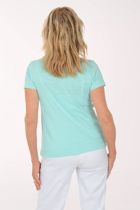 A woman wearing a short sleeve blue top with a turtle print.