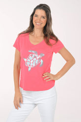 A woman wearing a short sleeve pink top with a turtle print.