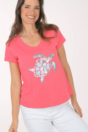 A woman wearing a short sleeve pink top with a turtle print.