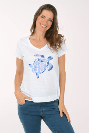 A woman wearing a short sleeve white top with a turtle print.