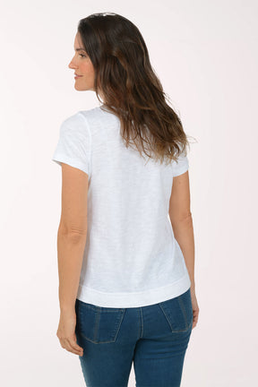 A woman wearing a short sleeve white top with a turtle print.