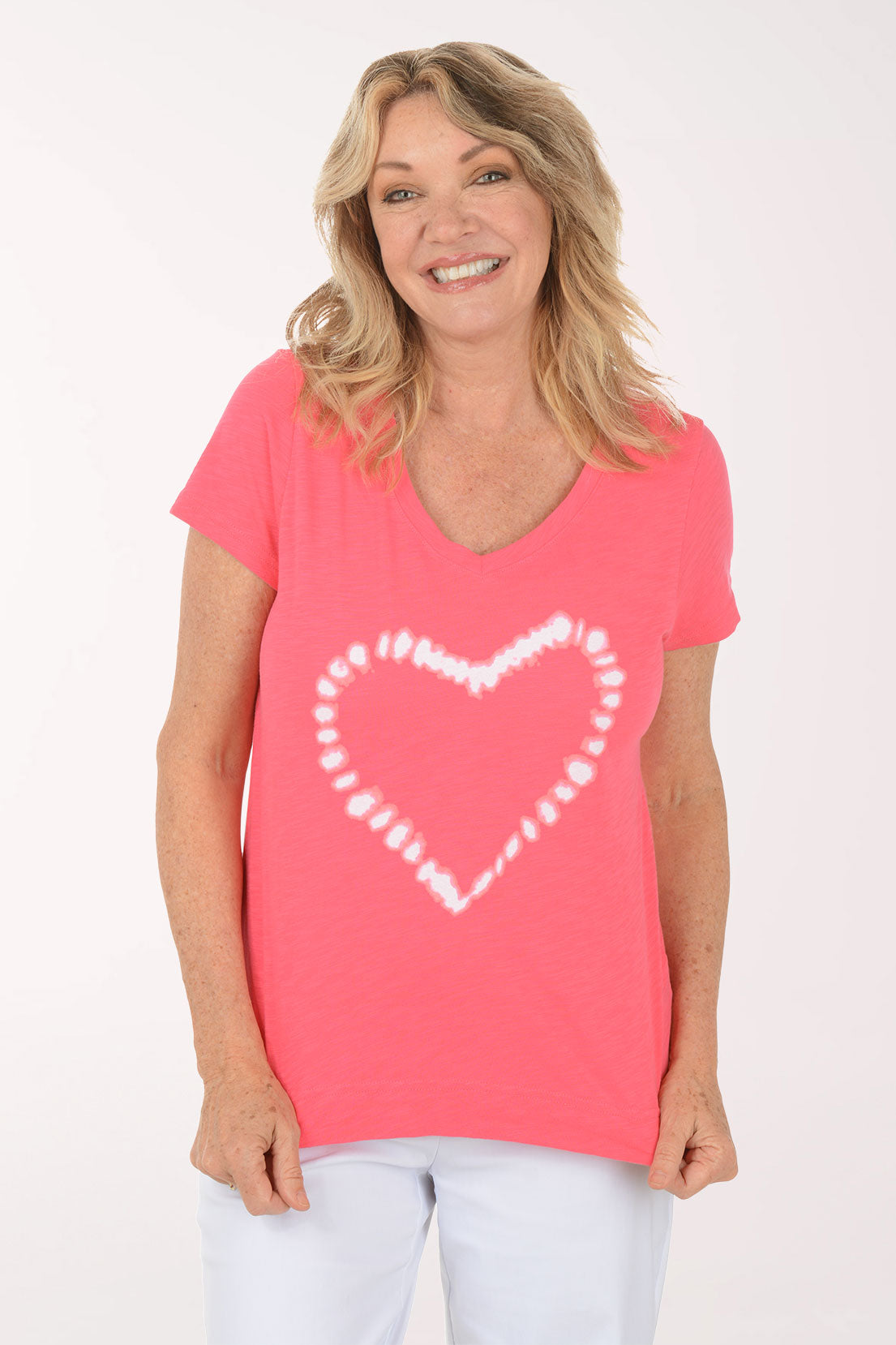 A woman wearing a short sleeve pink top with a heart print.