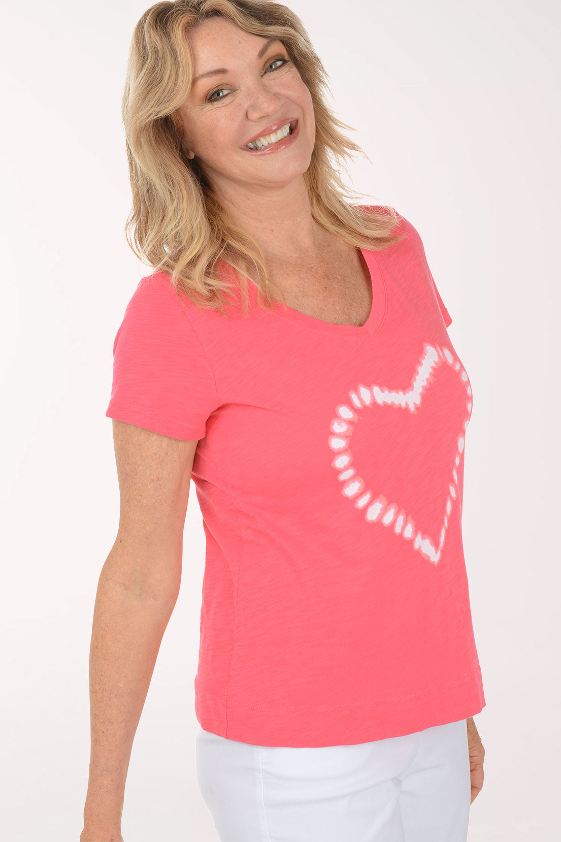 A woman wearing a short sleeve pink top with a heart print.